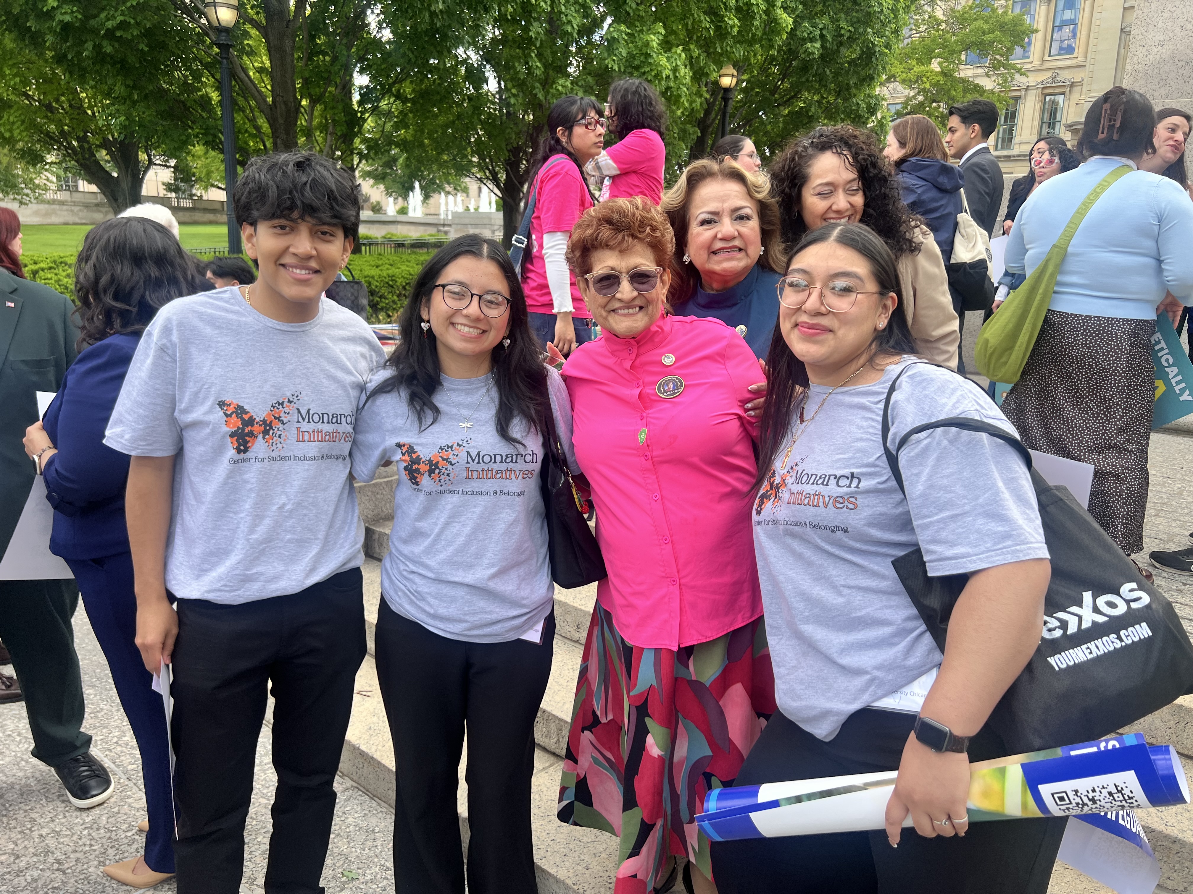 Monarch students posed with IL Latine legislators and advocates in the IL state captiol with trees in the background. 